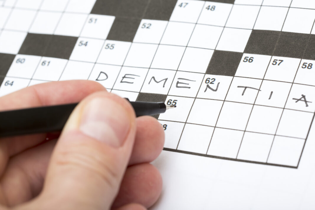 un homme remplit une grille de mots-croisés
